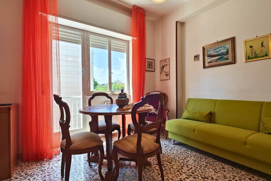 Soggiorno luminoso con comodo divano e tavolo da pranzo, ideale per rilassarsi leggendo libri su Siracusa, la Sicilia e la storia d’Italia