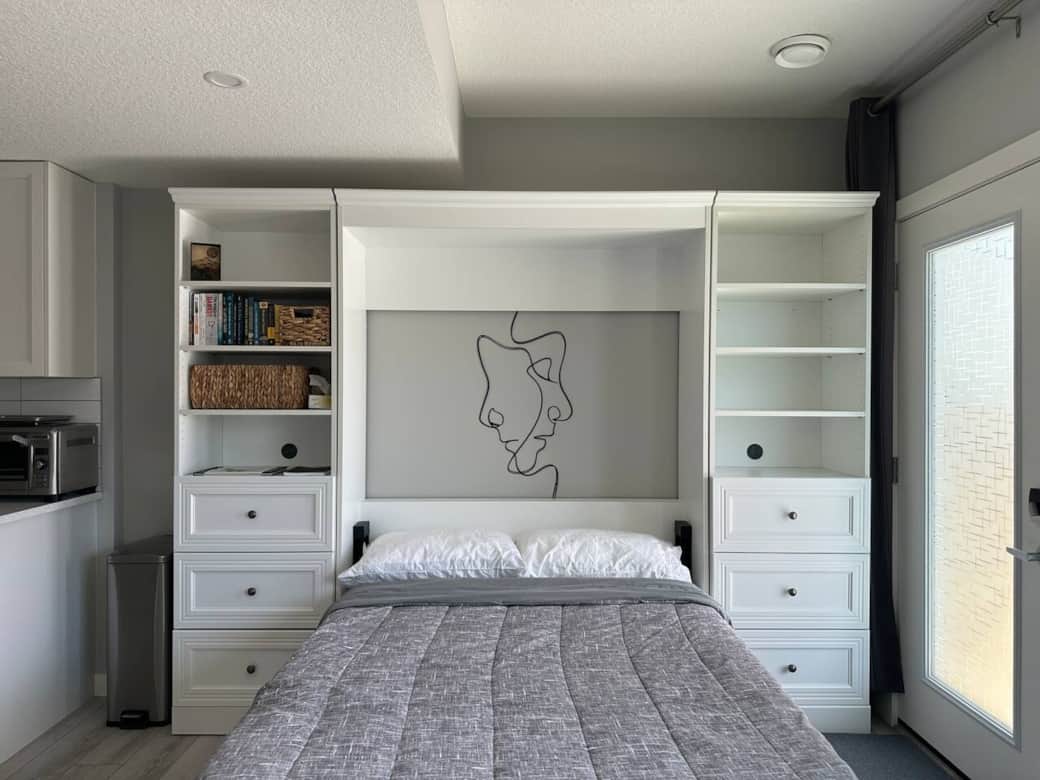 Bright and modern living space with a sleek Murphy bed, smart storage, a cozy desk setup, and comfortable seating. Perfect for relaxing, working, or enjoying a quiet night in.