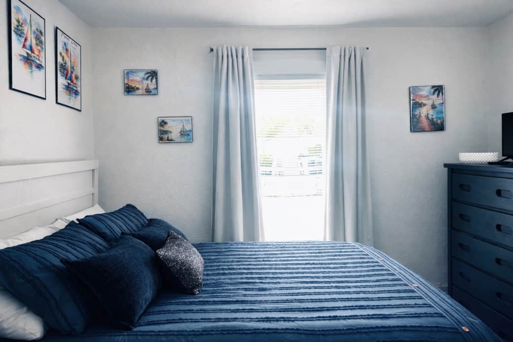 Stylish bedroom with plush bedding, colorful art.
