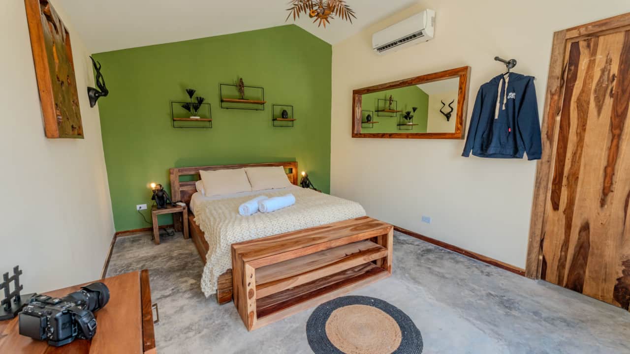 Eco-cabin bedroom with green accent wall and handcrafted wood furniture in Coronado, Panama