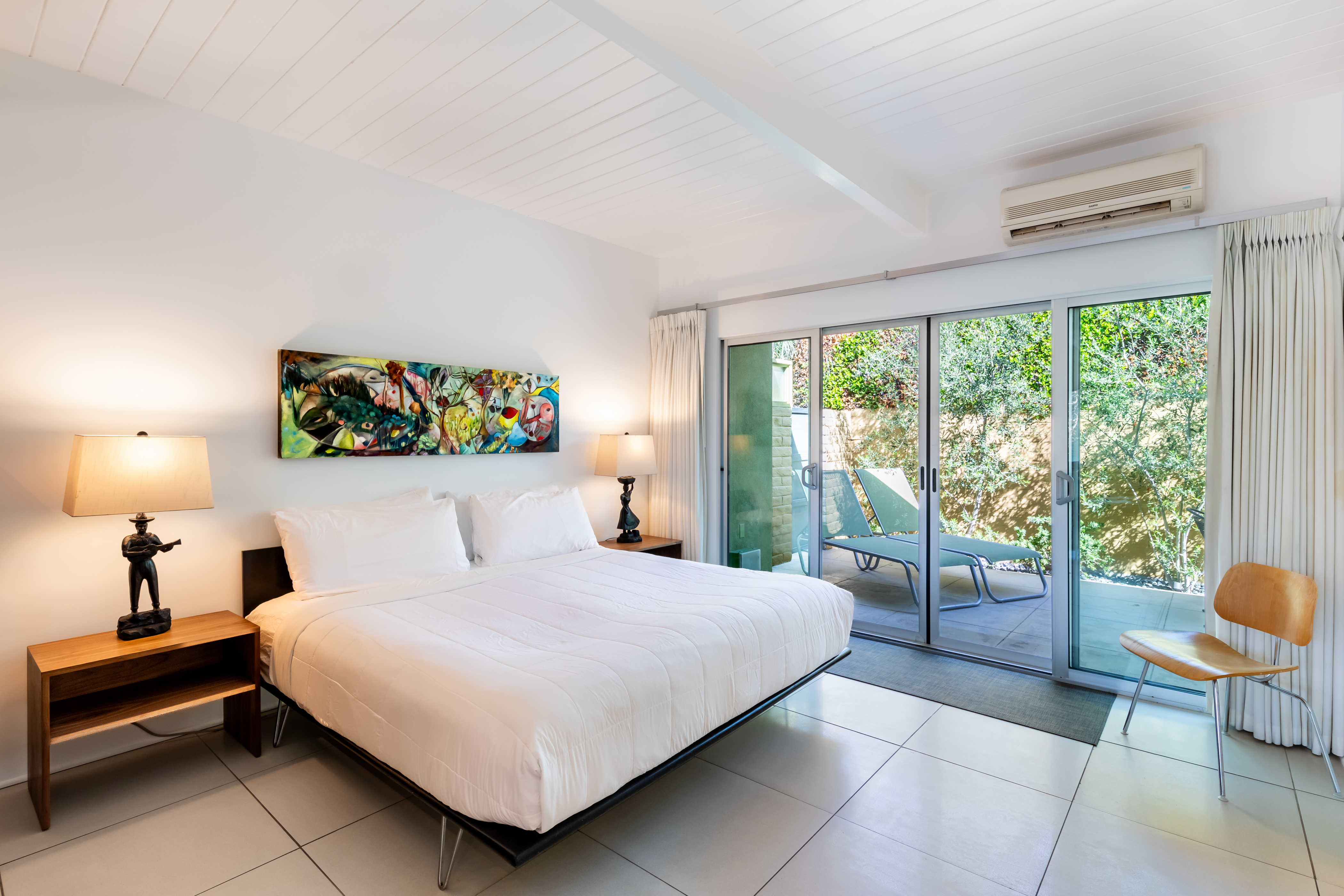 A hotel room with a large bed, tile floor, and sliding glass doors leading to a balcony