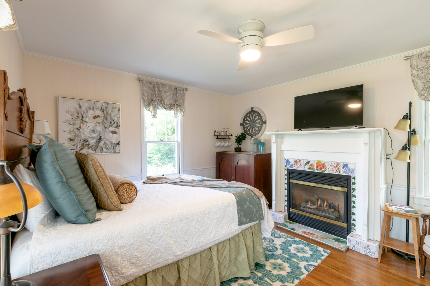 Queen size bed in front of a gas fireplace. Plenty of natural light and a kitchenette.