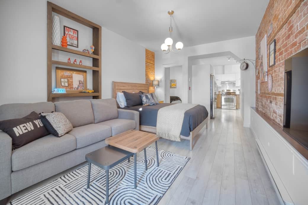 Une décoration inspirée du style loft new-yorkais. Le salon à aire ouverte propose un espace convivial et lumineux, comprenant un divan confortable et un lit queen supplémentaire, idéal pour les familles.  