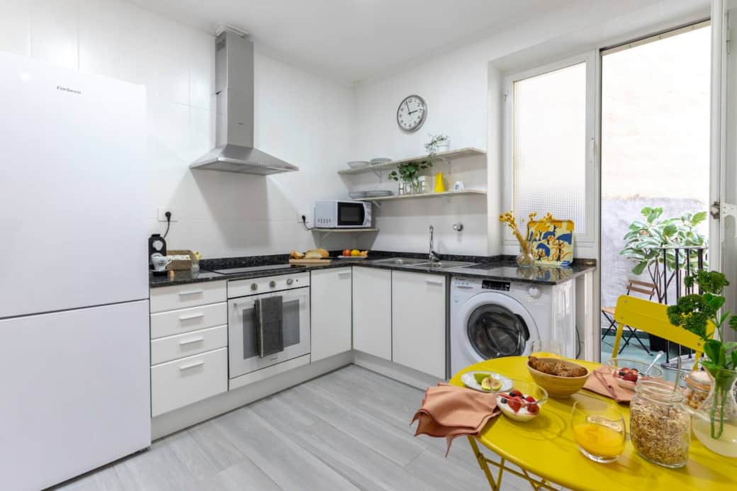 Cocina equipada con frigorífico, lavadora, horno y microondas.