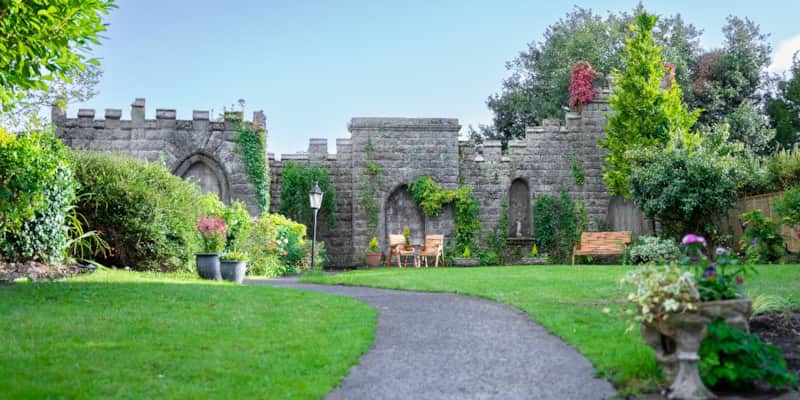 The Secret Garden with its castle-style stone wall, lawn and winding path