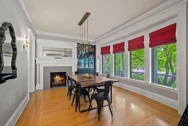 Sun-filled dining room with a cozy fireplace, statement lighting, and large windows