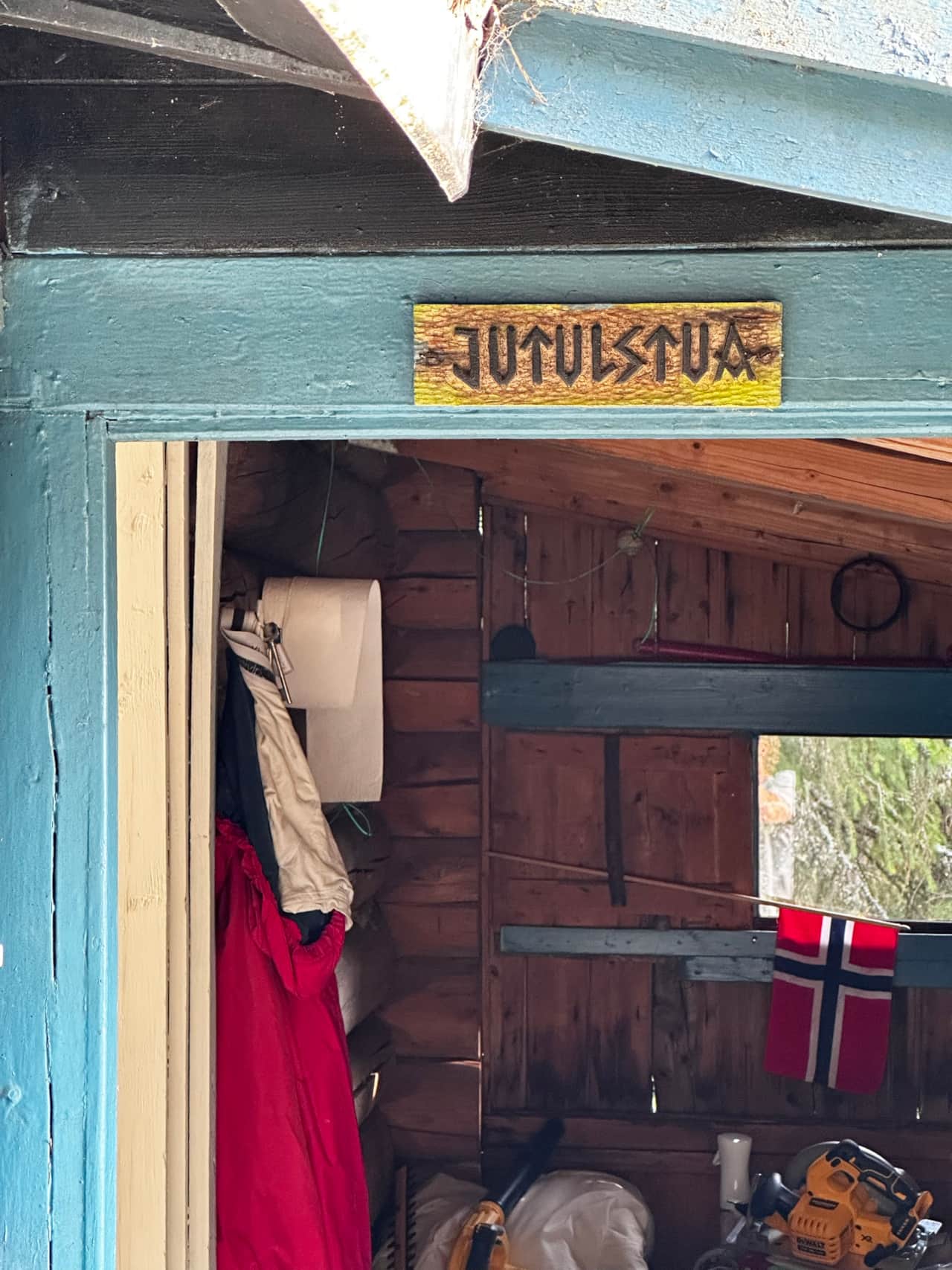 Tømmervegger og lyseblå dørkarm inne i Jøtulstua