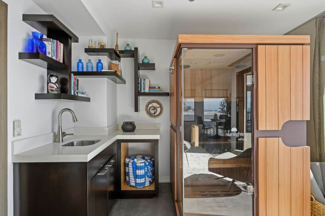 The private sauna sits beside a sink and shelving, creating a convenient, spa-like setup.