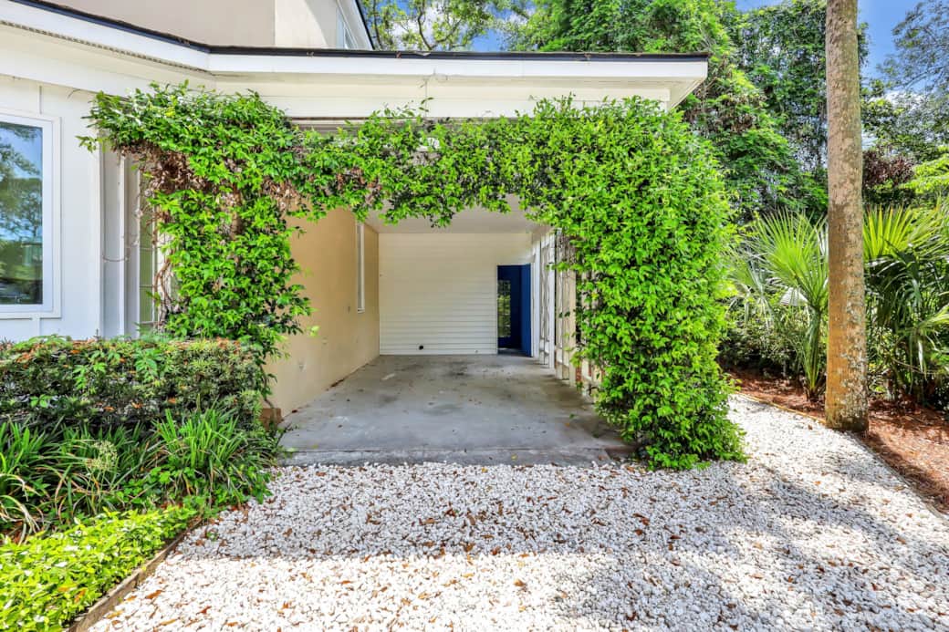 This quaint portico is adorned with greenery and jasmine. Through the portico is the laundry room.