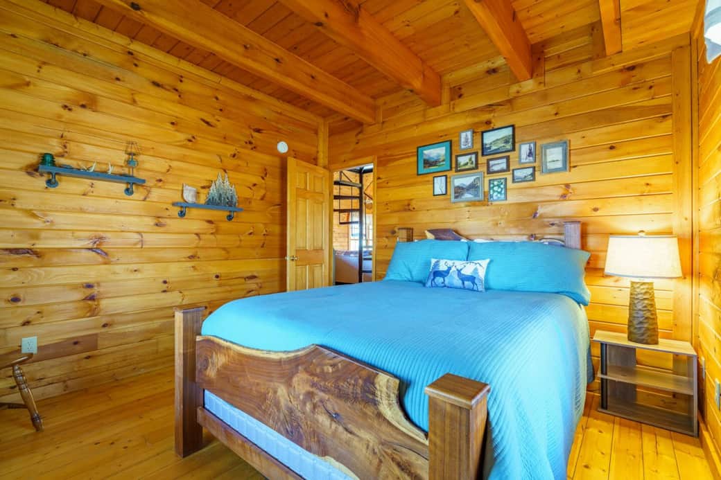 A cozy Cabin room with our queen bed with two large windows for great light and views of the surrounding woods.
