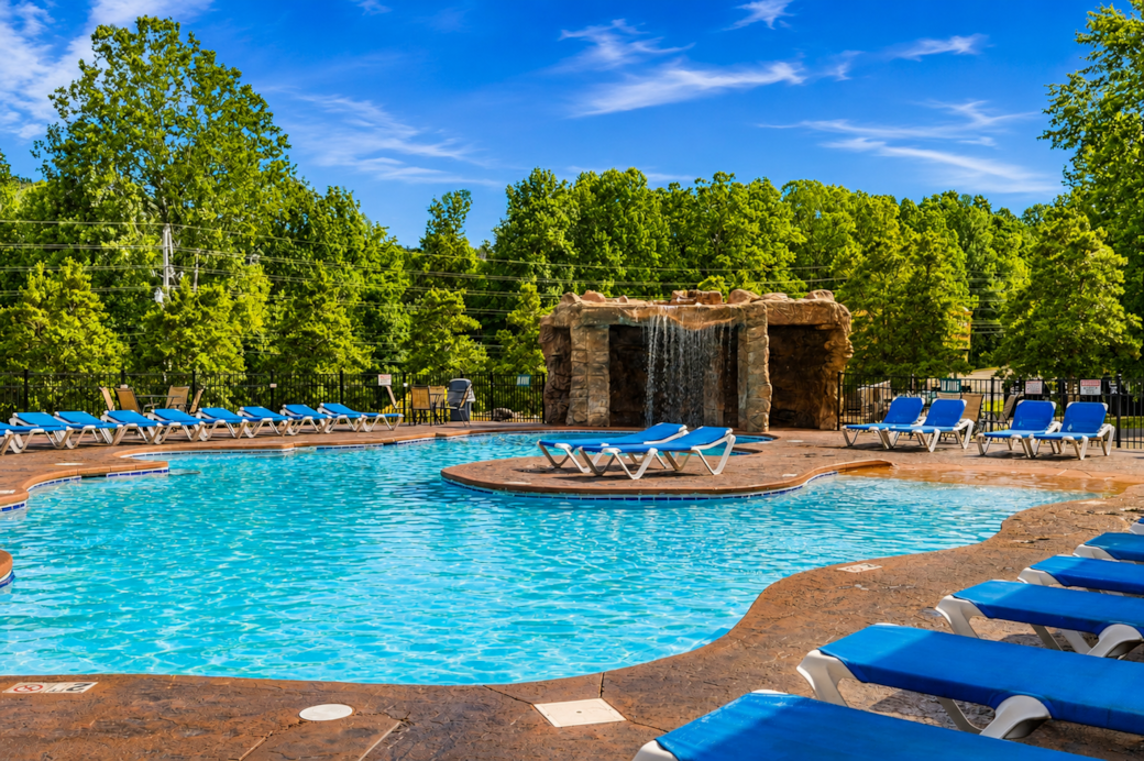 Relax by the resort pool on a sunny Smoky Mountain day, featuring plenty of loungers and waterfall Relax by the resort pool on a sunny Smoky Mountain day, featuring plenty of loungers and waterfall
