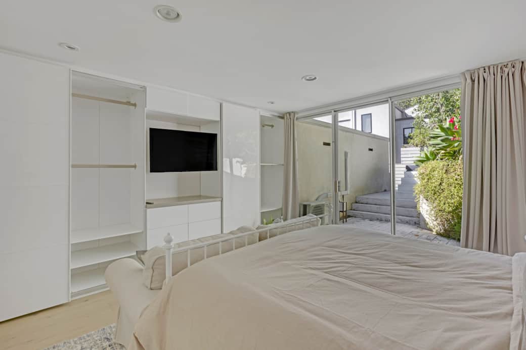 Bedroom with built-in TV, plush bed, and sliding doors to a private outdoor space. Bedroom with built-in TV, plush bed, and sliding doors to a private outdoor space.