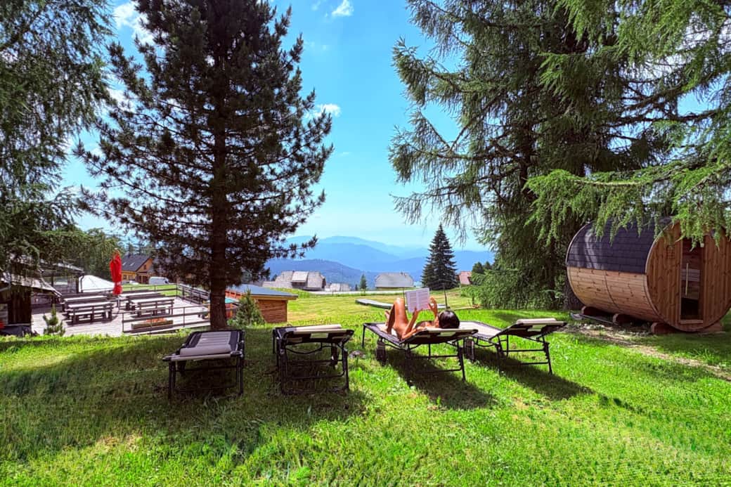 Sonnenliegen auf der Sommerwiese mit Fasssauna und Bergpanorama Sonnenliegen auf der Sommerwiese mit Fasssauna und Bergpanorama