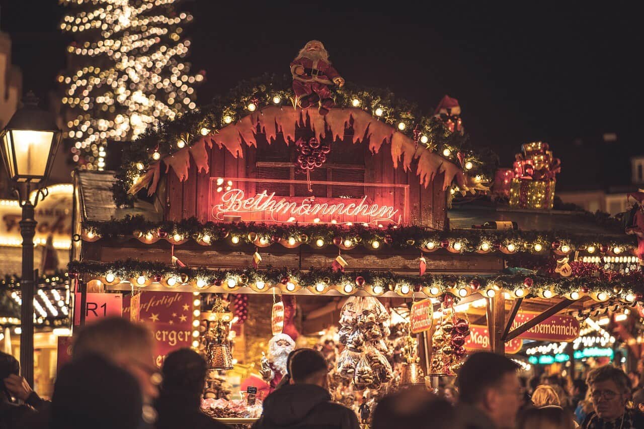 Belebter Weihnachtsmarkt mit festlich beleuchtetem Stand am Abend