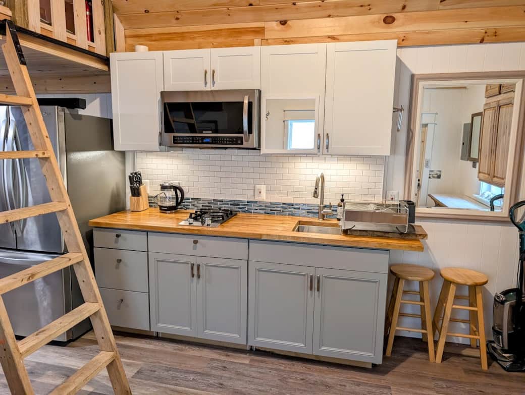 Kitchen with full fridge, microwave, sink and cooktop