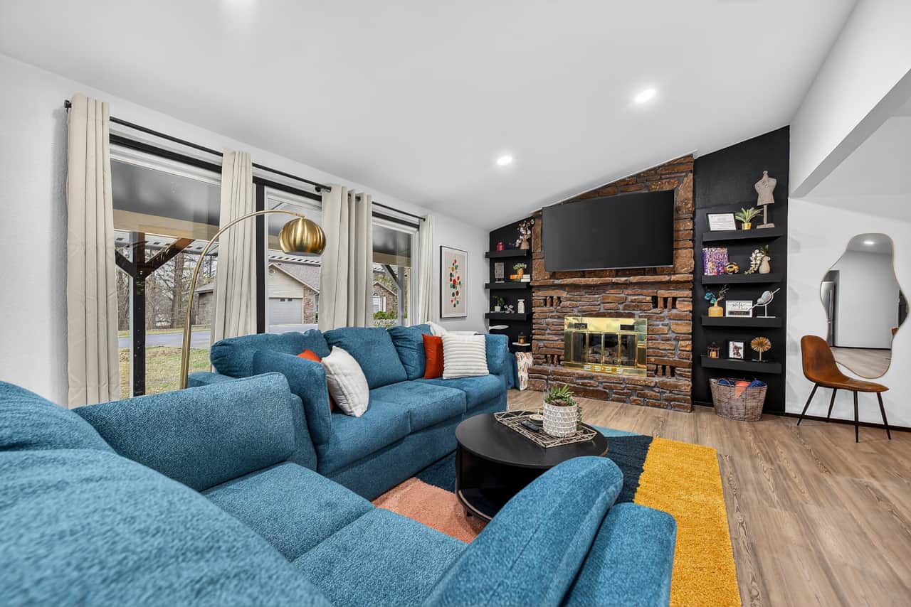 Open living room with comfy sofa, fireplace, and TV, flowing into kitchen and dining areas.