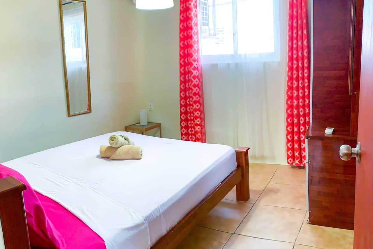 Air-conditioned bedroom with double bed, wardrobe, iron, ironing board, mirror, and towels. 