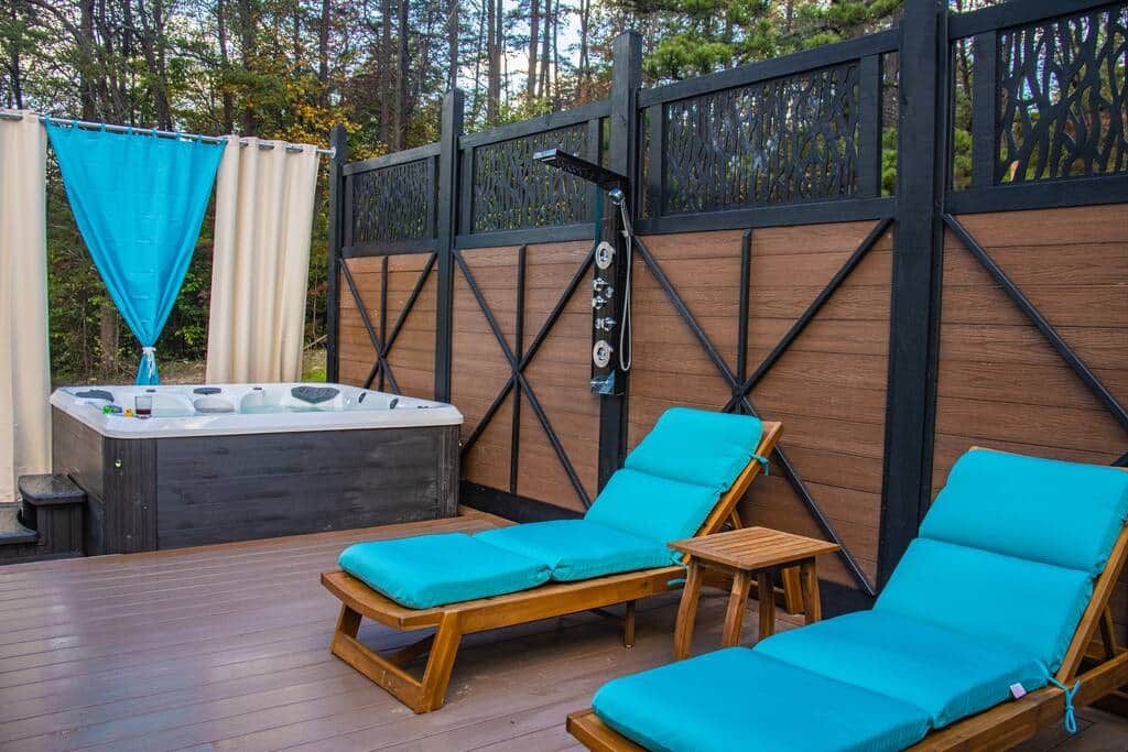 Next to the hot tub is a stylish outdoor shower with massaging jets