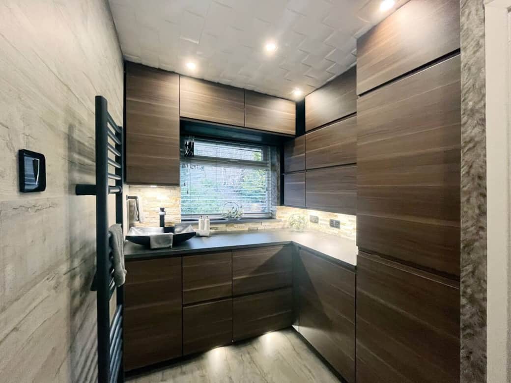 Sleek Utility Room: Enjoy the convenience of a fridge freezer, washer, dryer, and a stunning stone sink in this beautifully designed space with ample storage and ironing port.