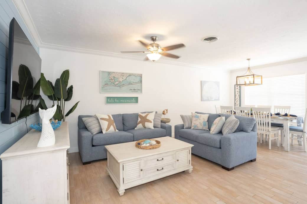 Upscale coastal living room: plush sofas, smart TV glow, island décor perfectly placed.