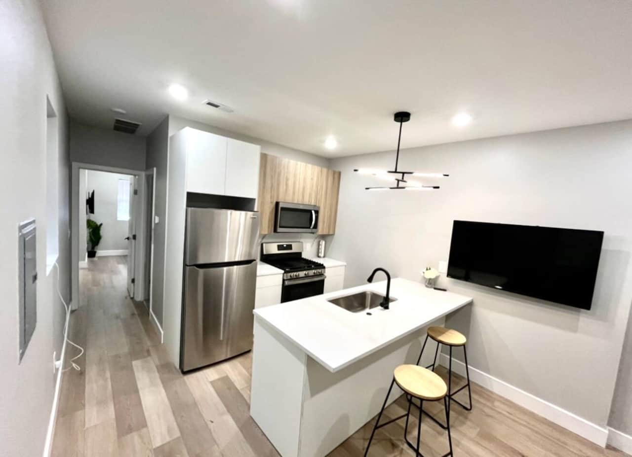 This modern kitchen is equipped with all your everyday amenities. It features high-quality cabinets, a refrigerator, a premium oven, a convenient microwave, a dishwasher, a toaster, a garbage disposal, and a stylish quartz island.