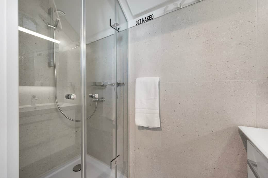 Badezimmer mit Dusche und Waschbecken. Hochwertige Fliesen und Armaturen