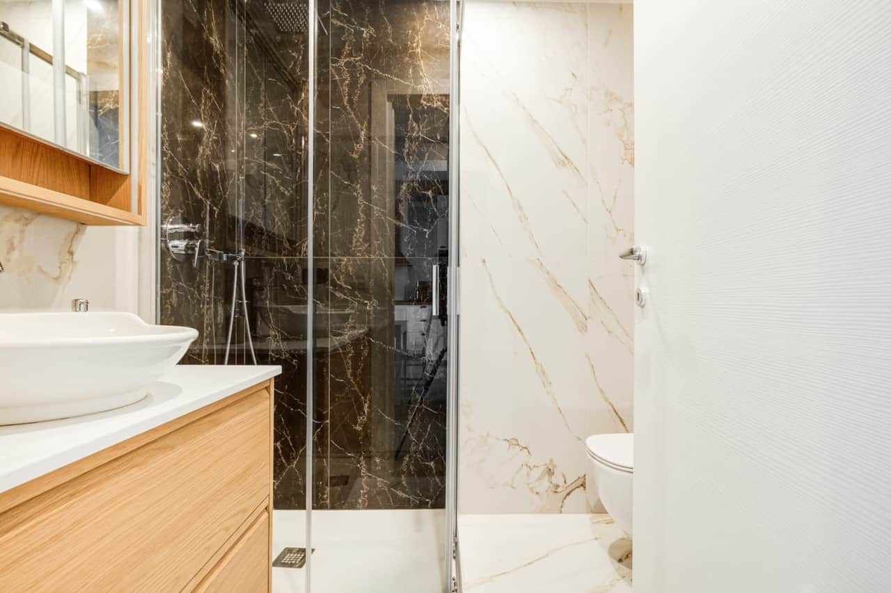 Bagno con doccia, arredato con colori armoniosi; legno e rivestimenti effetto marmo rendono queso ambinete unico e rilassante.