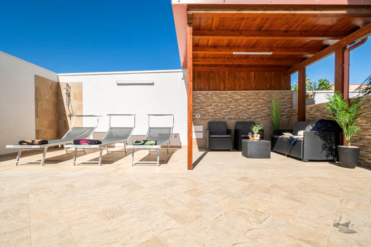Stylish patio with sun loungers and a shaded lounge area with comfortable sofas.