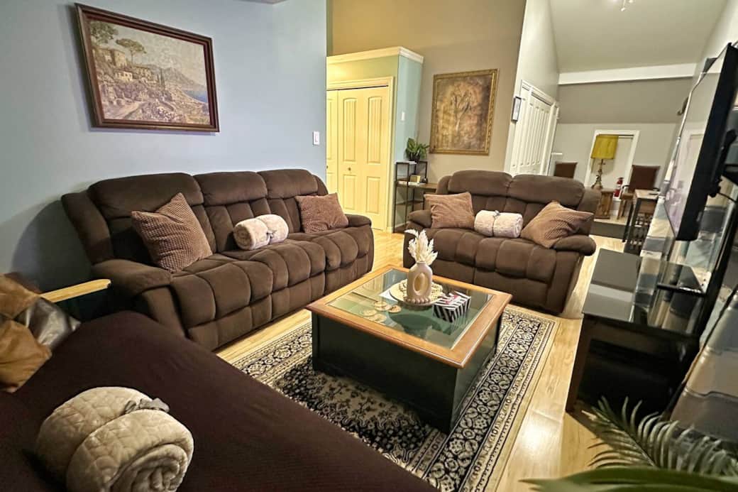 Spacious gathering area with two reclining sofas, one sofa bed, soft throws, and inviting lighting—perfect for relaxing after a day on the island.