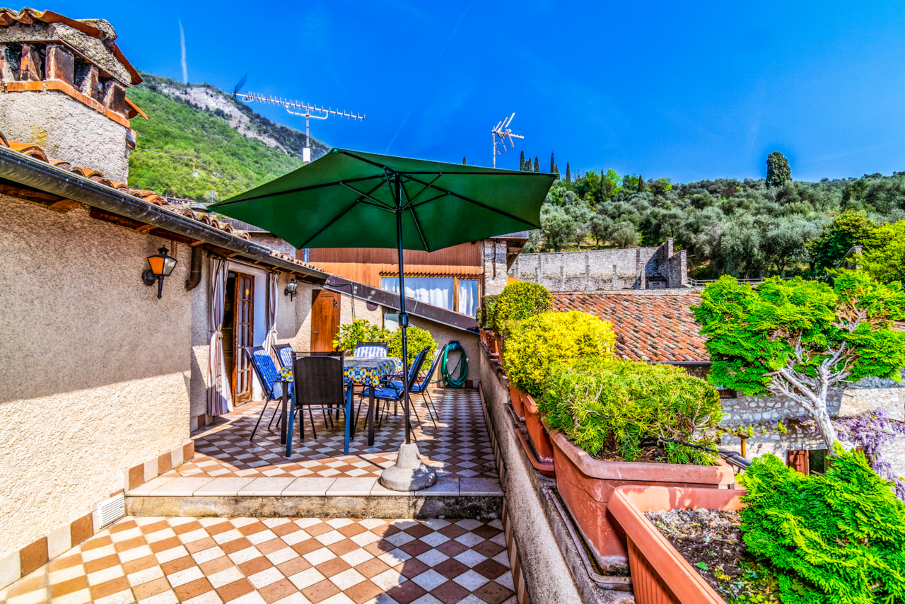 Die Terrasse ist mit Sonnenschirm, Tischen und Stühlen zum Essen und Entspannen im Freien ausgestattet.