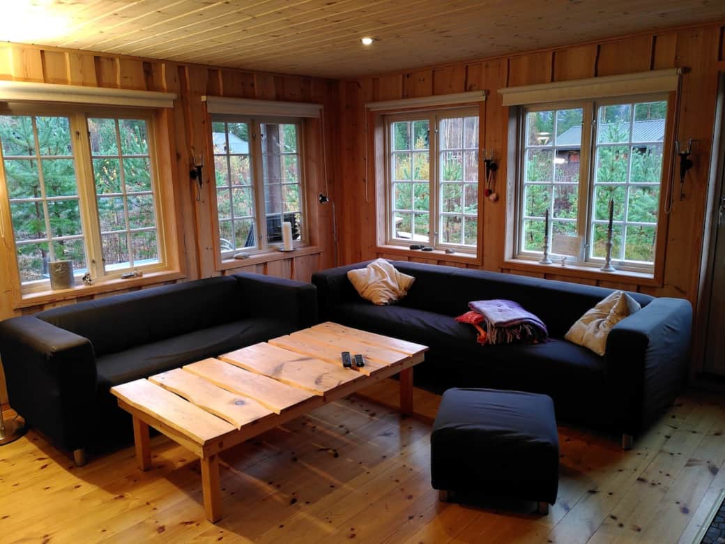 Der Wohnbereich ist mit zwei Sofas und einem Couchtisch ausgestattet. Die Fenster sind mit Rollos zur Verdunkelung versehen. Vom Wohnbereich aus gelangt man direkt auf die Terrasse.