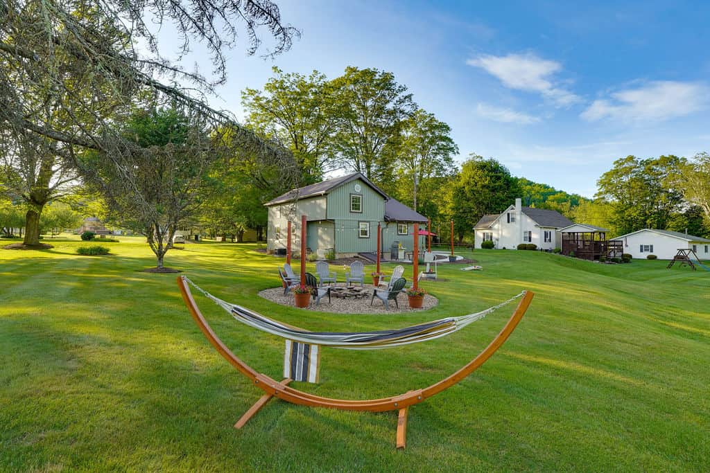 Fire pit, string lights, gas grill, cornhole, hammock, and a creek just steps away — your backyard a