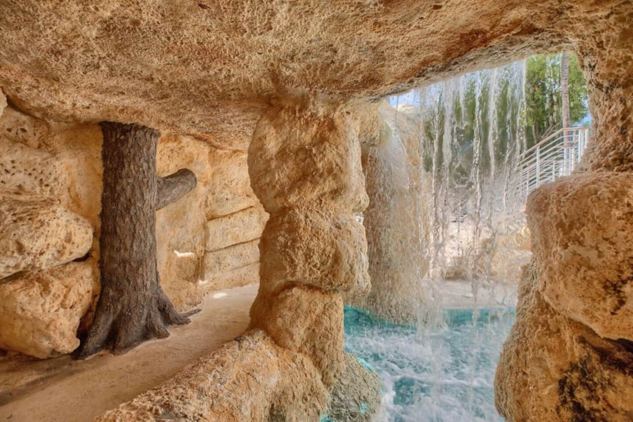The Grotto! A hidden hot tub oasis tucked behind a cascading waterfall, featuring powerful water pressure perfect for melting away stress and tension in a truly unique, cave-like setting.