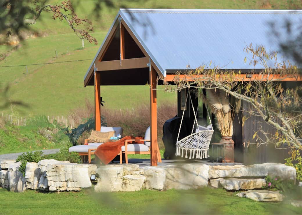 Luxury riverside deck with outdoor chairs at River Song Cabin Ripples Retreat Waitomo NZ)