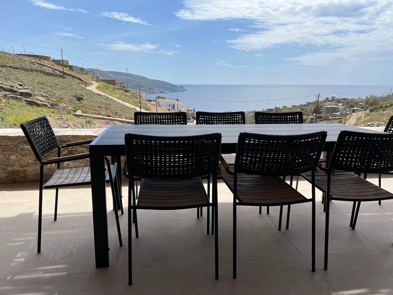 Outdoor dining table with black chairs on covered stone veranda, Koundouros, Kea