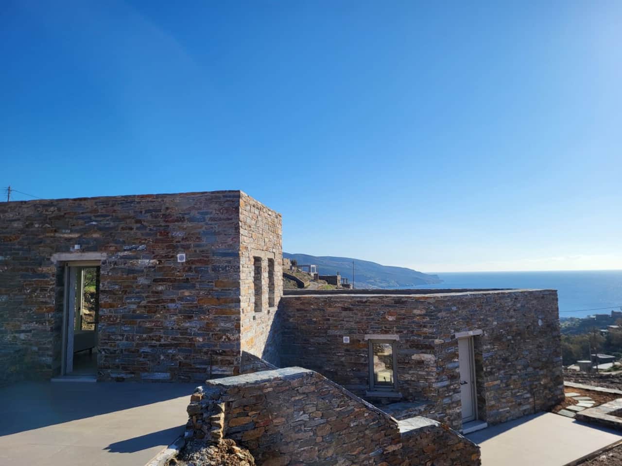 Stone holiday house exterior with hillside and Aegean Sea backdrop, Koundouros, Kea