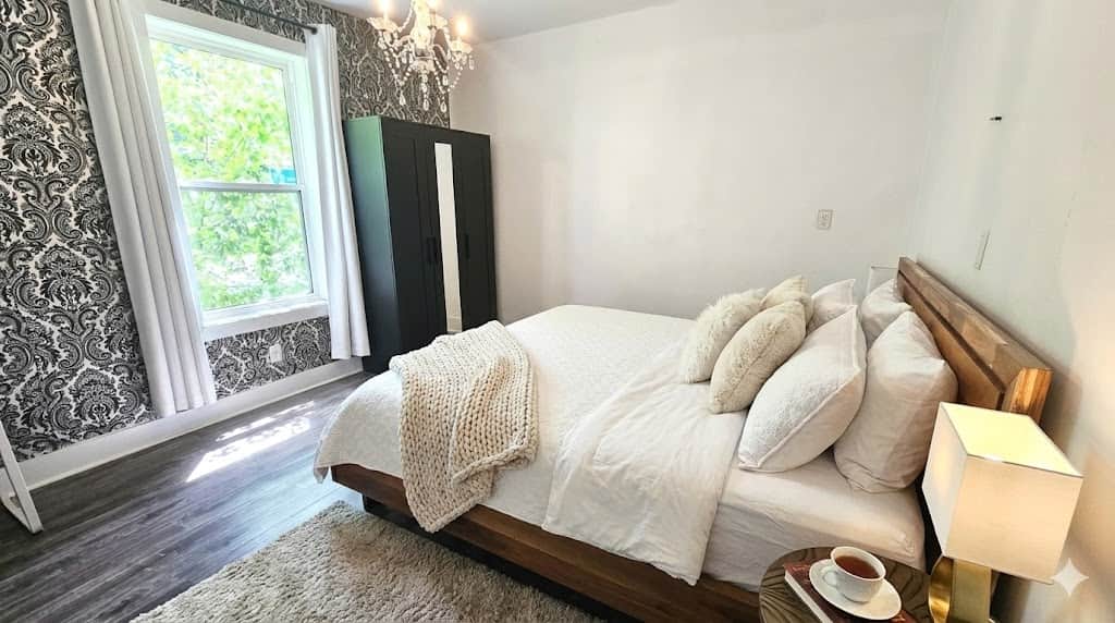 Bright primary bedroom with king-size bed, neutral decor, and cozy linens in a renovated main-floor 