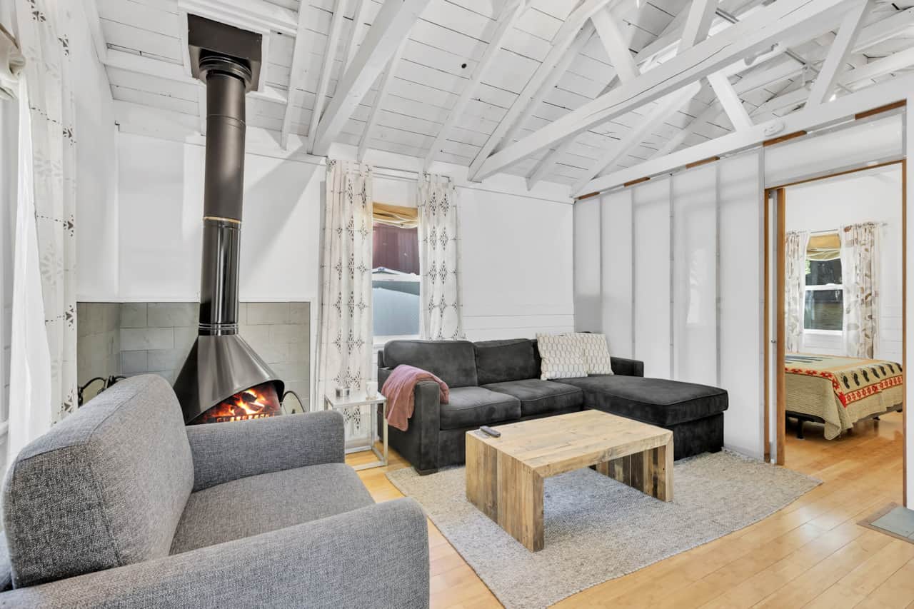 Enjoy the bright cabin living room with a cozy sofa bed, TV, and natural light.