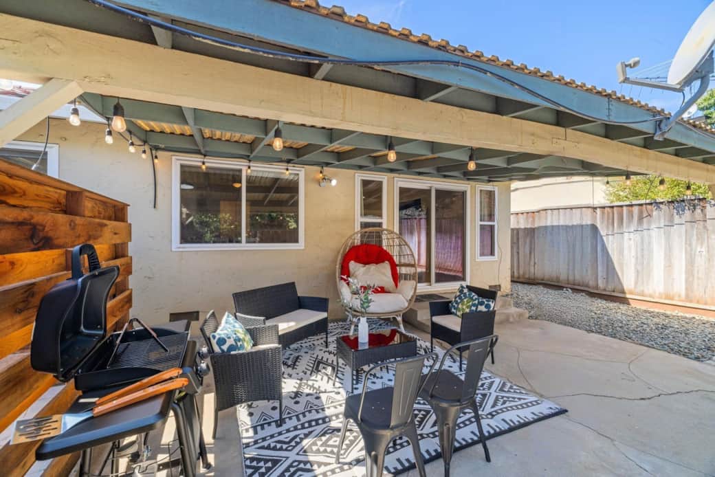 Covered patio with seating, grill, and string lights.