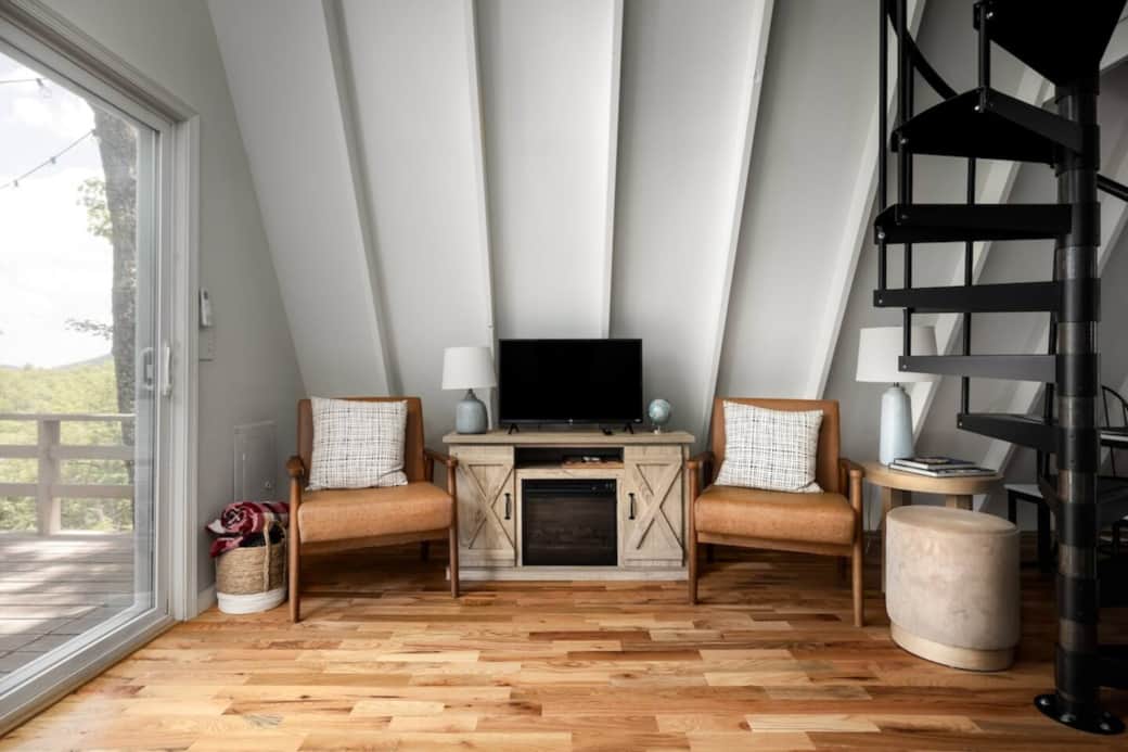 Unwind in our modern living space. Whether you're catching up on your favorite show or enjoying the view through the glass doors, it's a great way to recharge. Grab a book, sink into the leather armchairs, and let the mountain vibes take over.