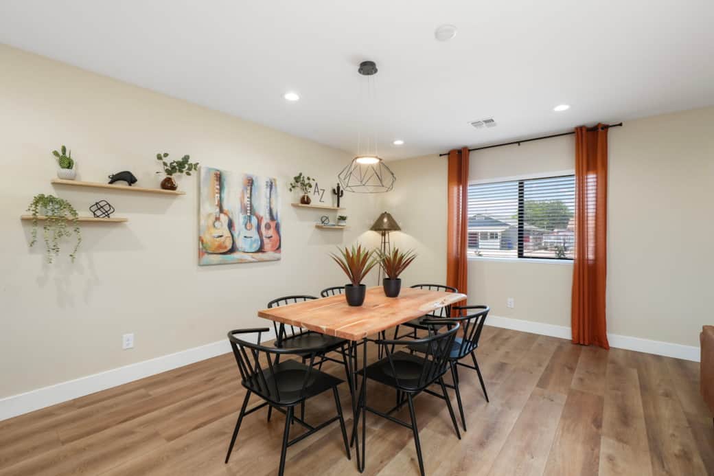 Bright dining area with a modern geometric light and warm, sun-soaked accent curtains.