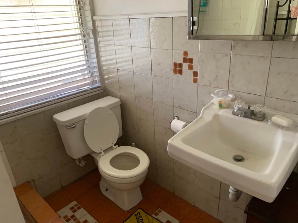 Original Unit 2 bathroom at Casa Citron showing an older finish and fixtures, with plumbing and layout that worked well prior to modernization.