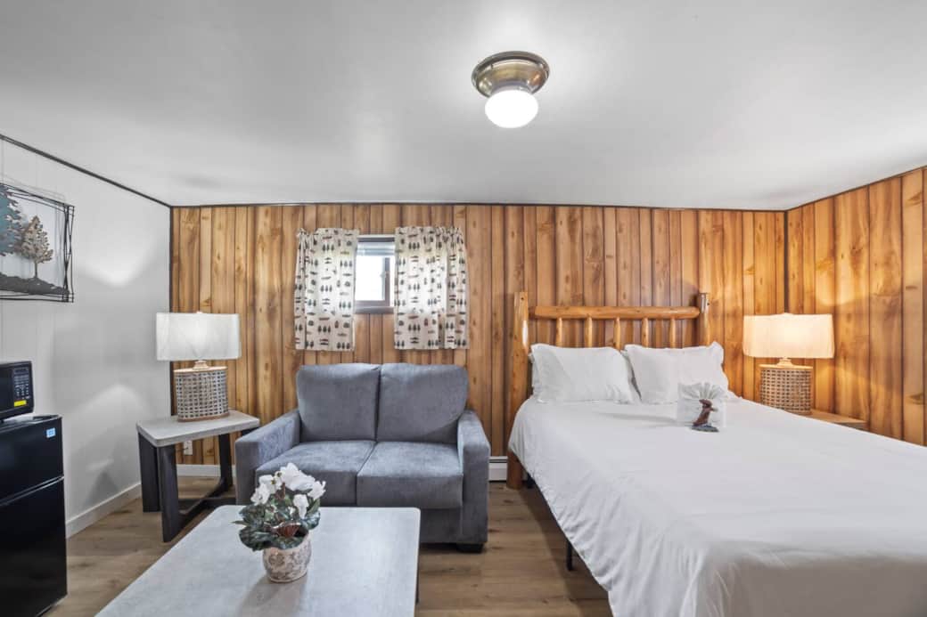 Cozy retreat with warm wood paneling, plush bed, and a comfy seating nook - perfect for unwinding after a day’s adventures.