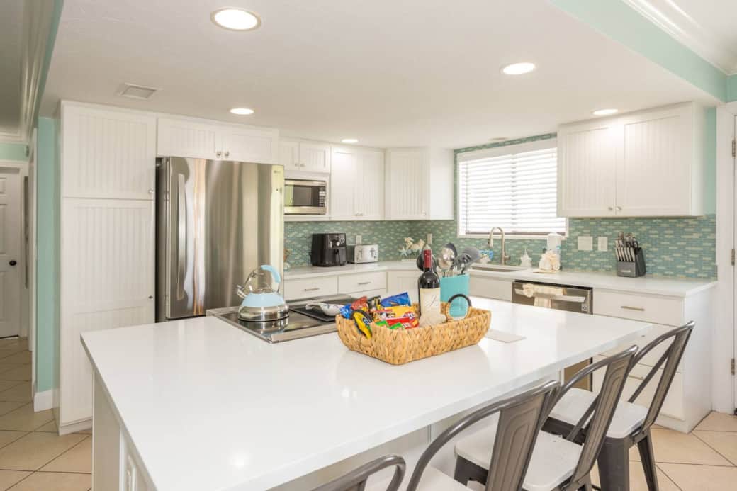Expansive open-concept coastal kitchen—stainless shine, sea-glass backsplash, made for vacay feasts.