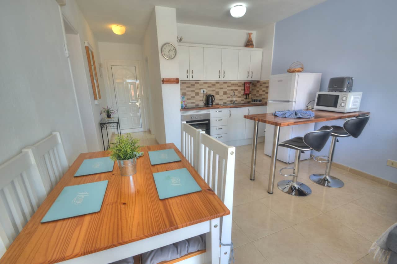 Mesa con sillas y cocina.