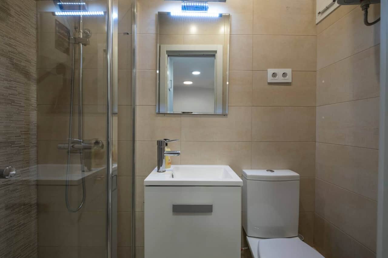 Baño con ducha de obra, mampara y lavabo con mueble