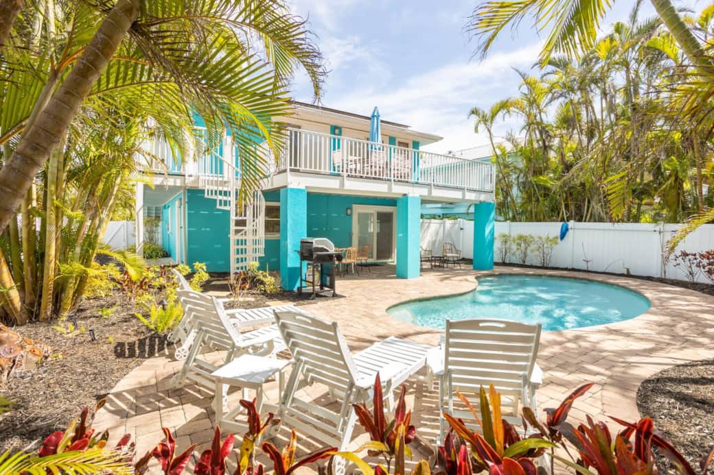 Private heated pool and spa beside the AMI coastal home—palms, loungers, steps to sand.
