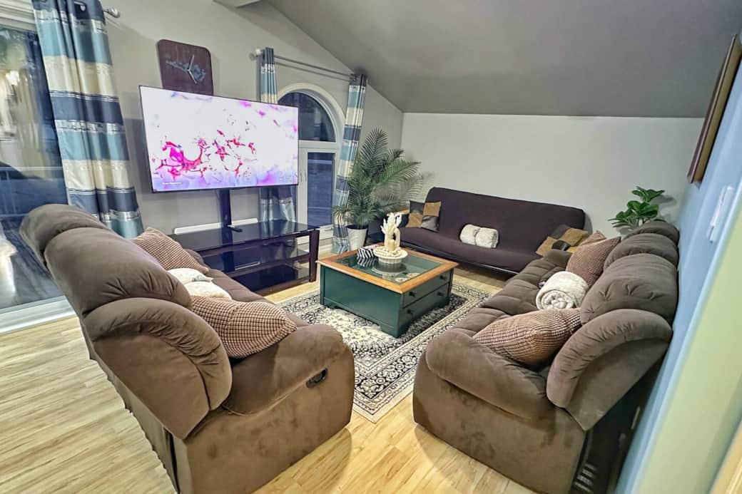 Open-concept living space featuring recliner sofas, large windows, and a 55” smart TV for movie nights.