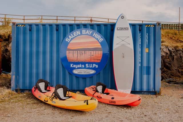 Kayaks and a paddleboard beside the Salen Bay Hire sign