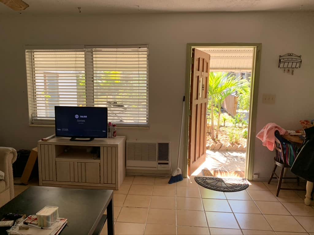 Before renovation: Unit 2 living room at Casa Citron with limited natural light and wall air conditioner, prior to full modernization and redesign.